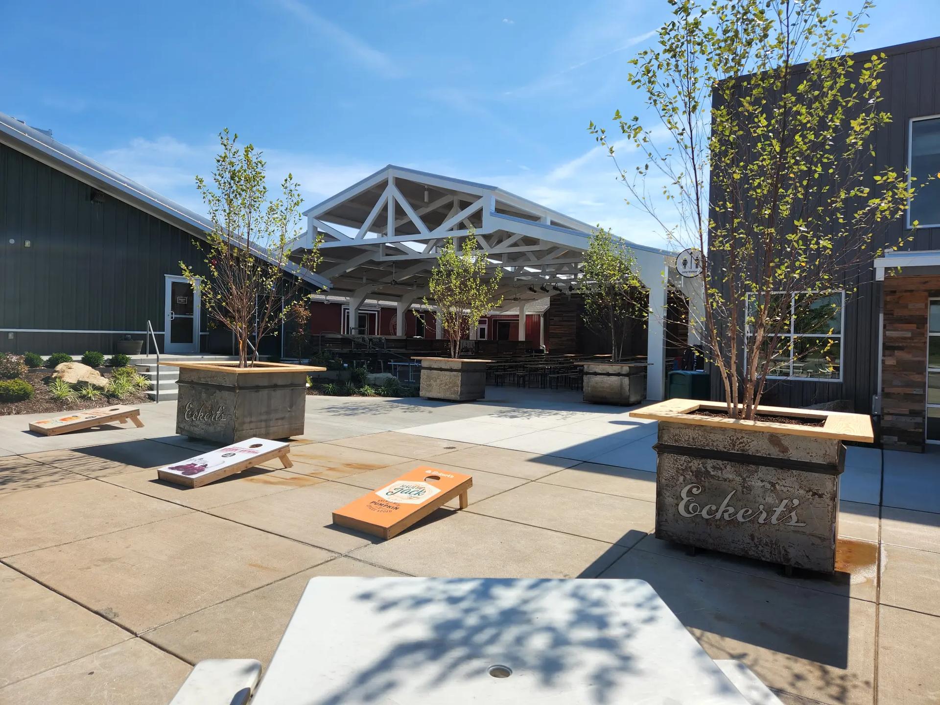 Large white timber-frame pavilion with exposed trusses and outdoor seating at Eckert's Cider Shed entertainment venue