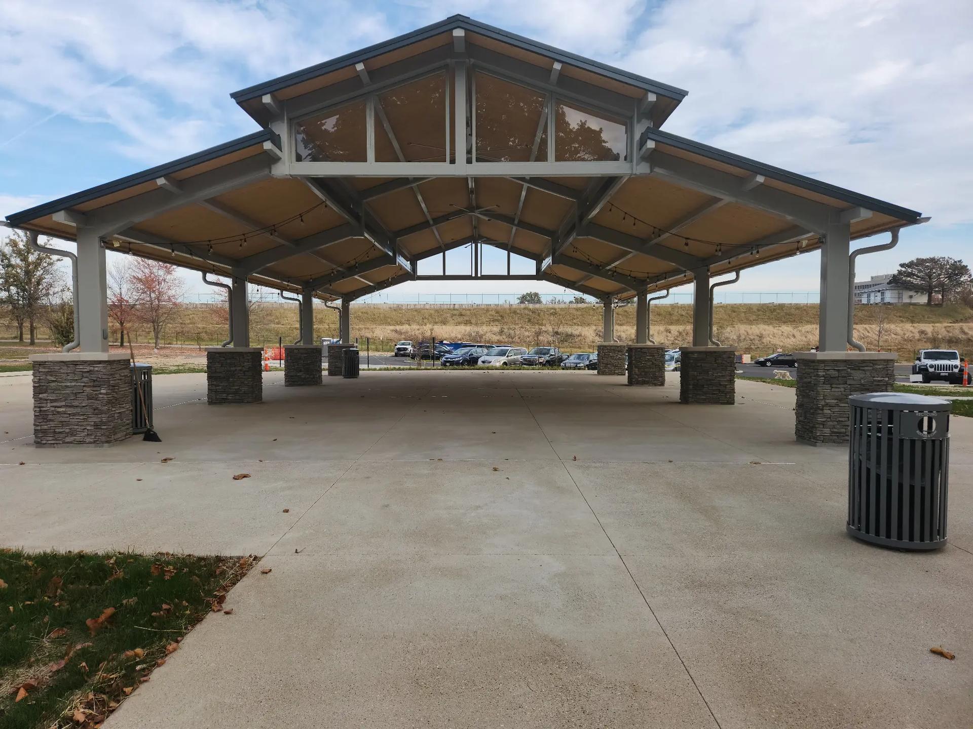 Open-air park pavilion with steel frame structure supported by decorative stone masonry columns